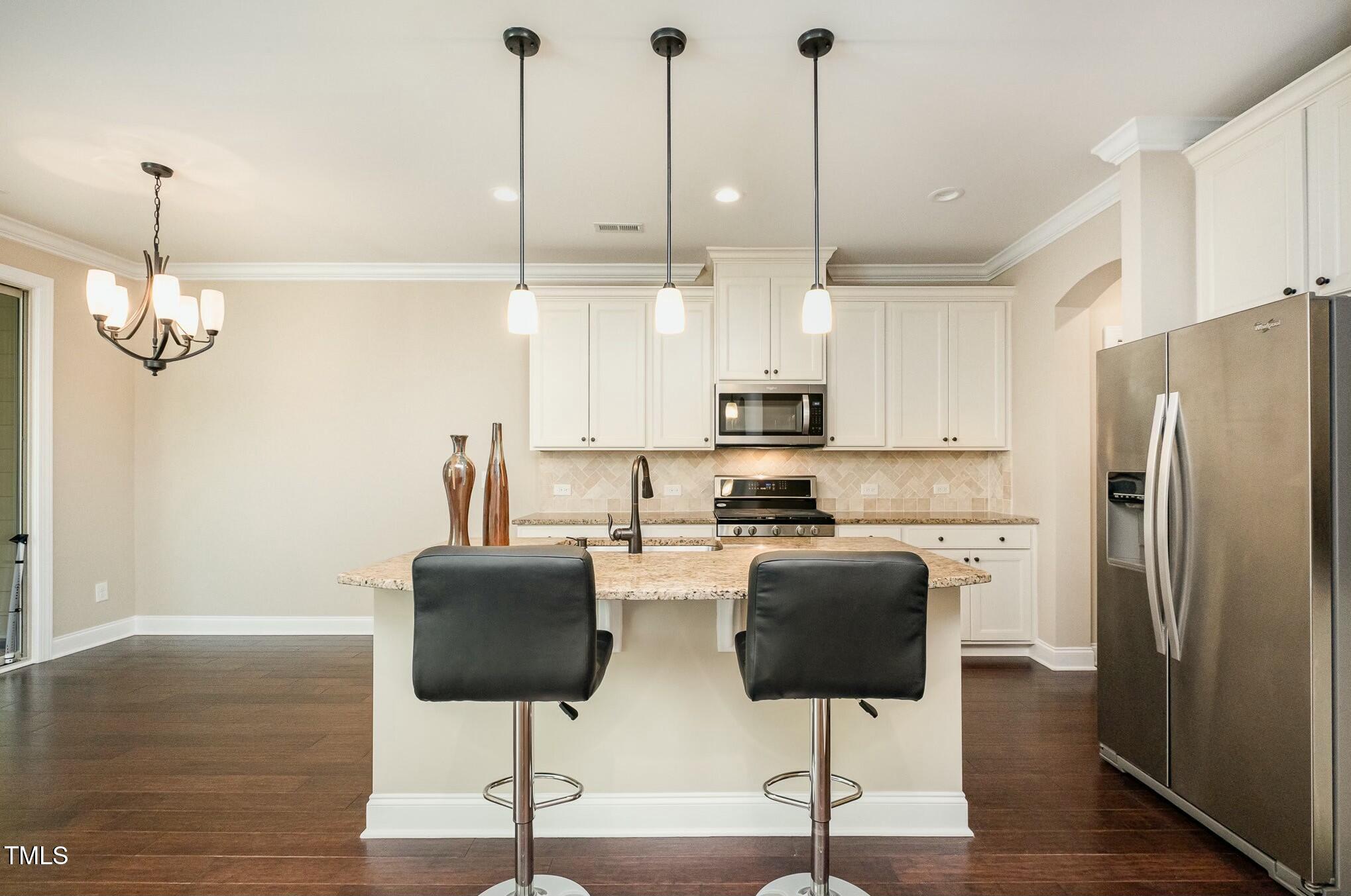 1335 Catch Fly Lane Durham, NC 27713 - Photo 13 of 30 a kitchen with stainless steel appliances kitchen island granite countertop a refrigerator a stove a microwave oven a sink with island and chairs in it