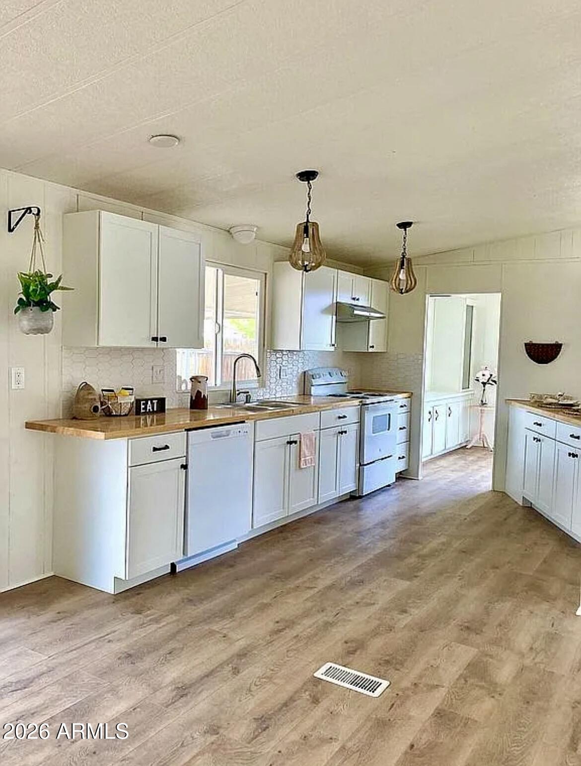 a large kitchen with stainless steel appliances granite countertop a stove a sink dishwasher and white cabinets with wooden floor