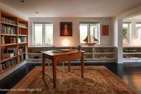 a living room with a piano and a book shelf