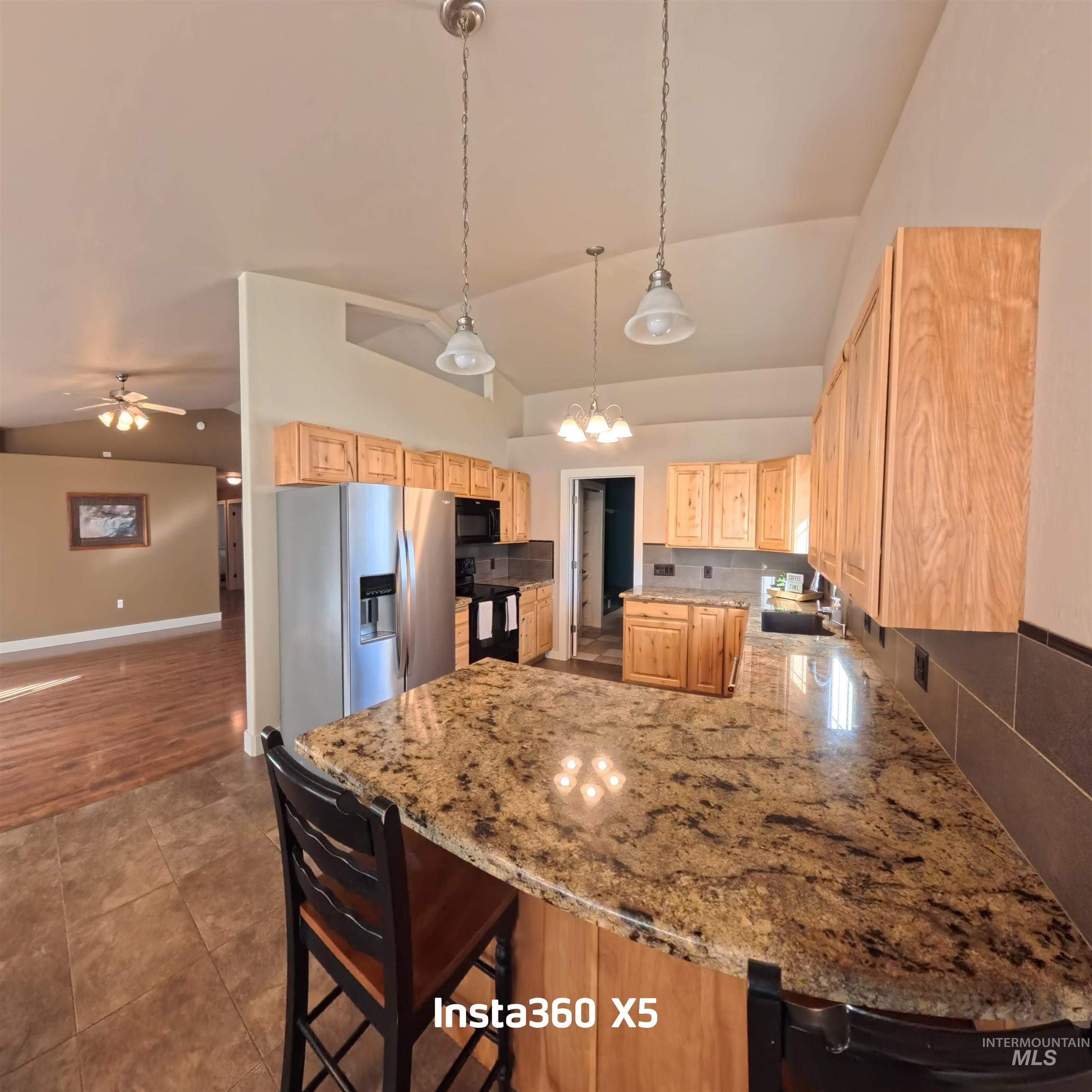 891 North Pointe Drive Twin Falls, ID 83301 - Photo 10 of 46 Kitchen with a peninsula, a breakfast bar, black appliances, light brown cabinets, and lofted ceiling