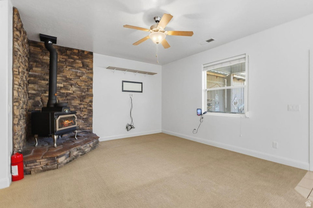 1001 Pine Valley Road Pine Valley, UT 84781 - Photo 11 of 49 Unfurnished living room featuring a wood stove, ceiling fan, and light carpet