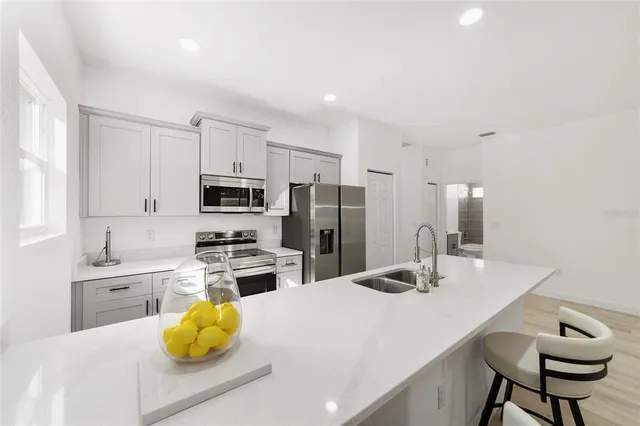 a kitchen with a sink a stove a refrigerator and white cabinets