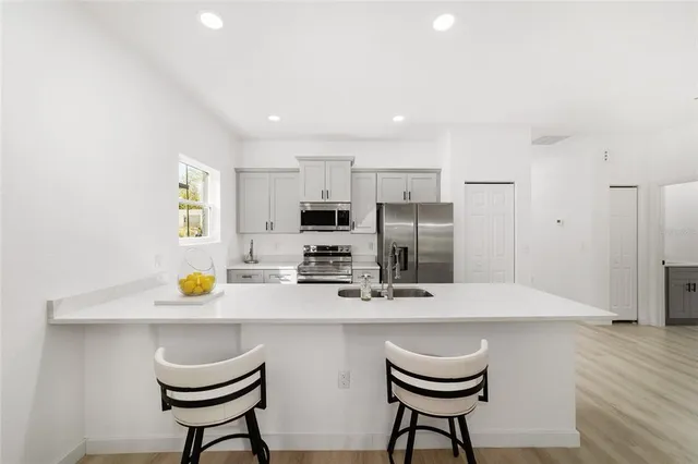 a kitchen with stainless steel appliances a sink a stove a refrigerator cabinets and dining table