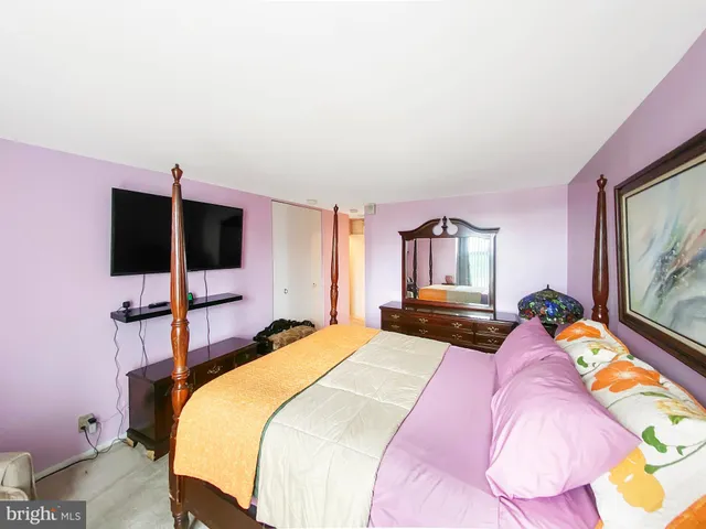 a bedroom with a bed and flat tv screen on dresser