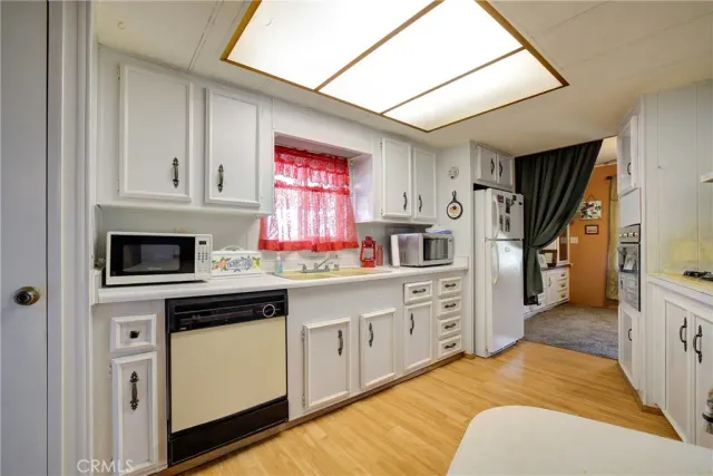 a large kitchen with stainless steel appliances kitchen island granite countertop a table chairs in it and wooden floors