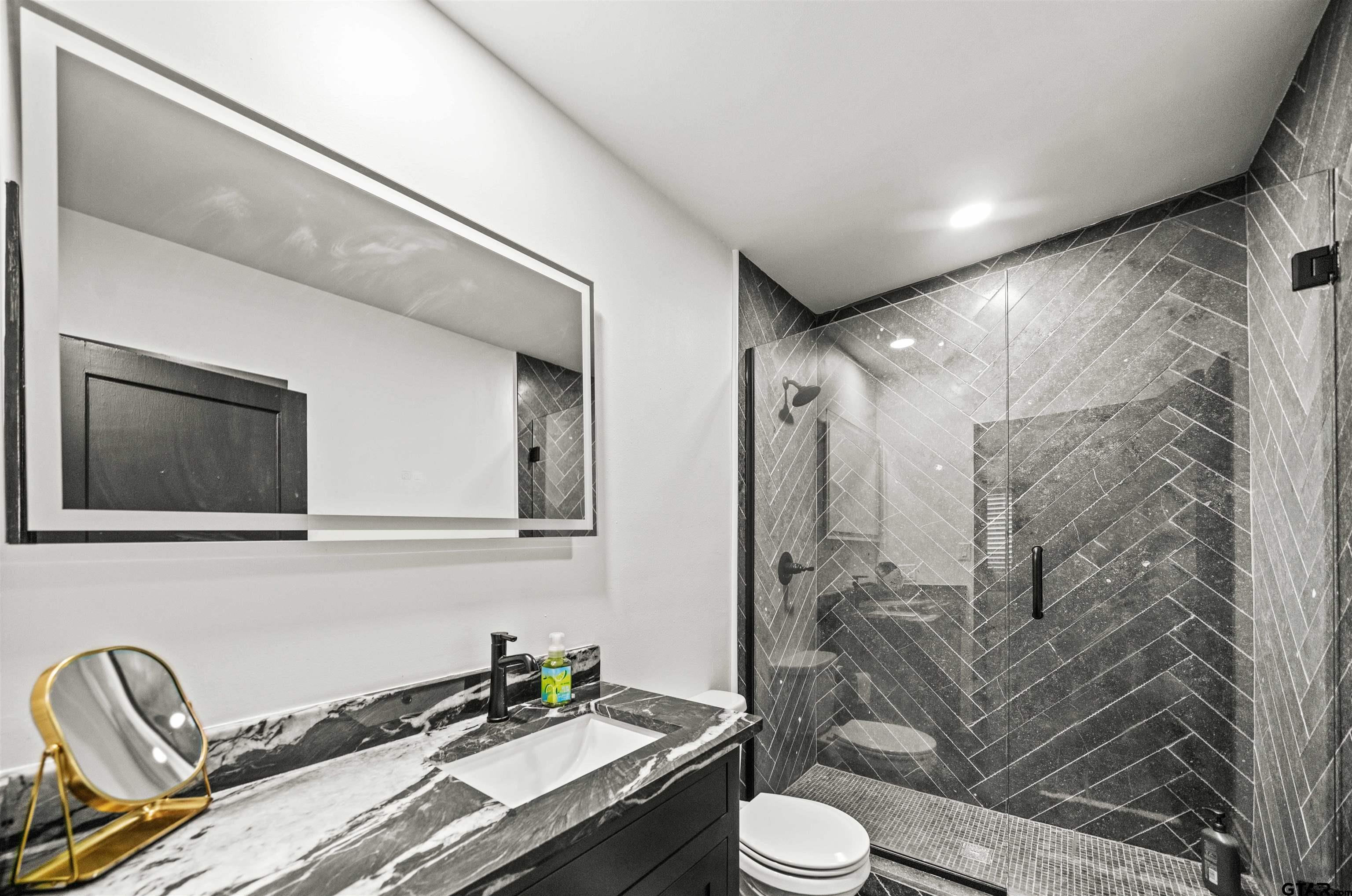 400 Lindsey Lane Tyler, TX 75701 - Photo 18 of 25 a bathroom with a granite countertop sink a toilet and shower