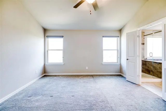 an empty room with chandelier fan and windows