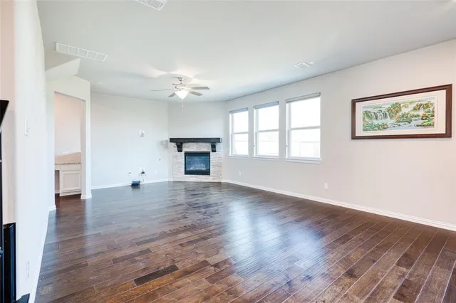 an empty room with wooden floor fireplace and a window