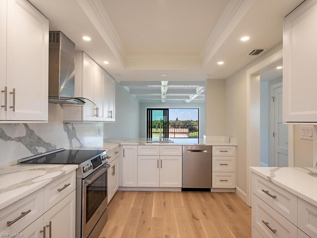 a kitchen with stainless steel appliances a white stove top oven cabinets and a wooden floor