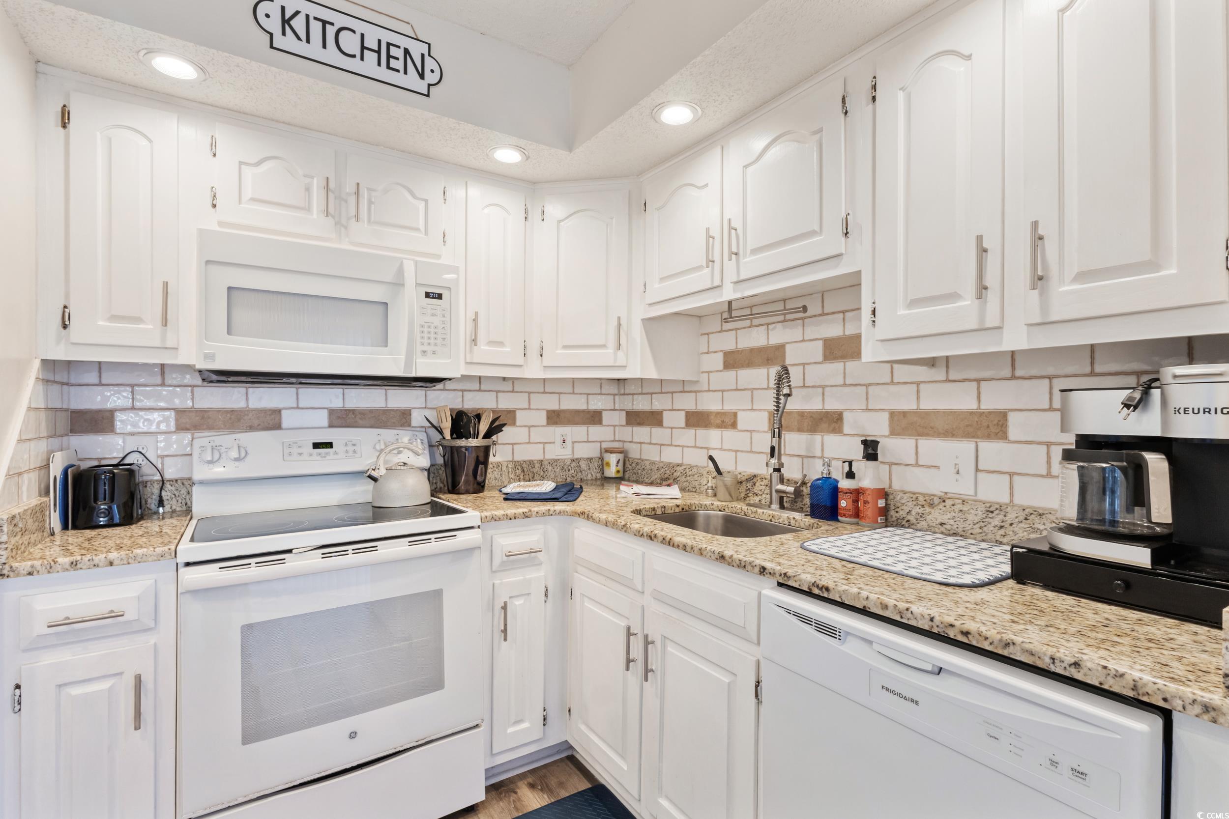 4242 Pinehurst Circle, Unit N3 Little River, SC 29566 - Photo 13 of 30 Kitchen with white appliances, white cabinets, light stone counters, and recessed lighting