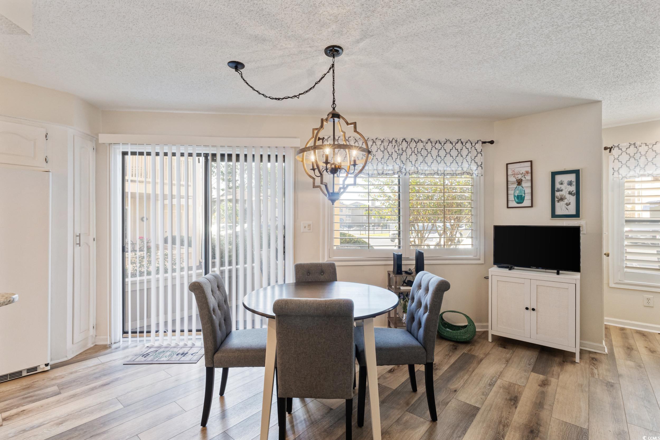 4242 Pinehurst Circle, Unit N3 Little River, SC 29566 - Photo 10 of 30 Dining space with a textured ceiling, light wood-type flooring, and a chandelier