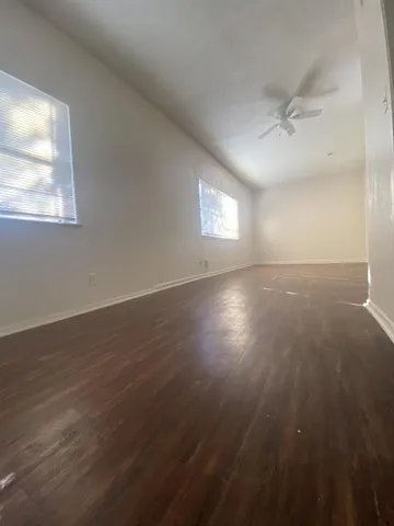 an empty room with wooden floor and windows