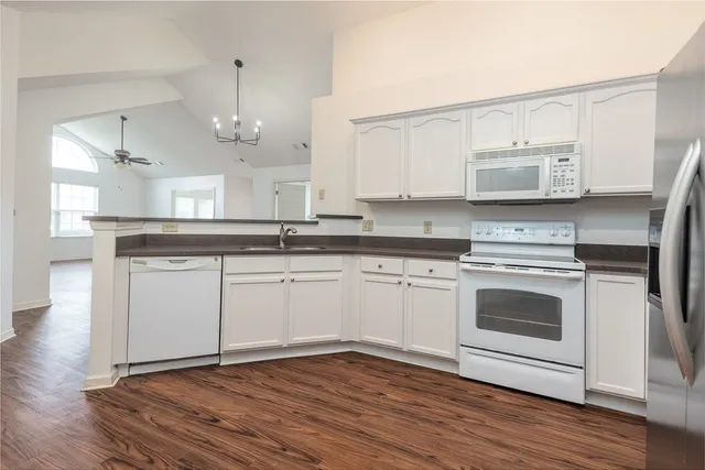 a kitchen with stainless steel appliances granite countertop a stove a sink and white cabinets