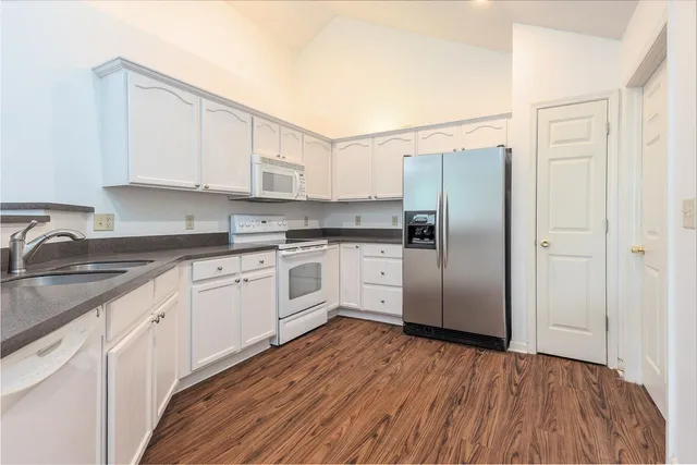 a kitchen with granite countertop a refrigerator and white cabinets