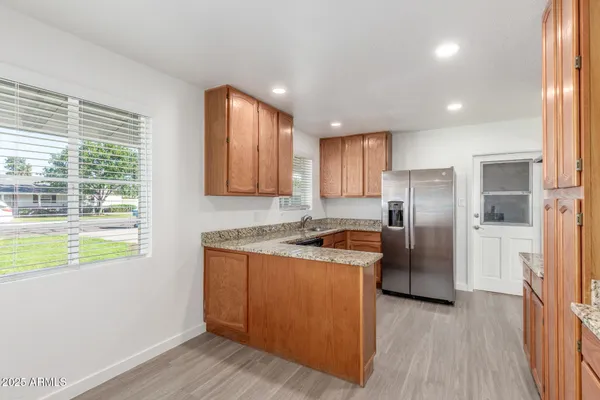 a kitchen with stainless steel appliances granite countertop a refrigerator a sink dishwasher a stove and a dining table with wooden floor