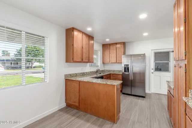 a kitchen with stainless steel appliances granite countertop a refrigerator a sink dishwasher a stove and a dining table with wooden floor