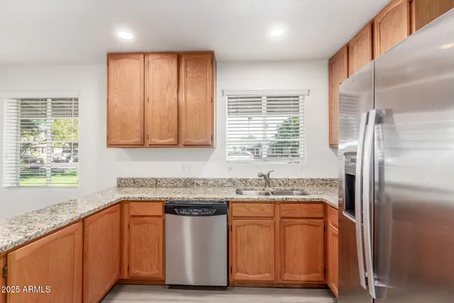 a kitchen with stainless steel appliances granite countertop a sink a stove a refrigerator and island with wooden floor