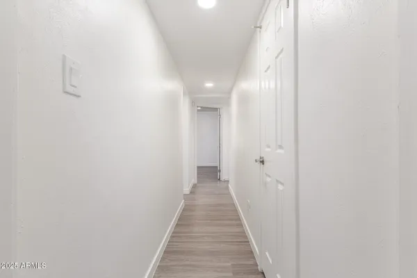 a view of a hallway with wooden floor and a bathroom