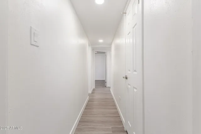 a view of a hallway with wooden floor and a bathroom