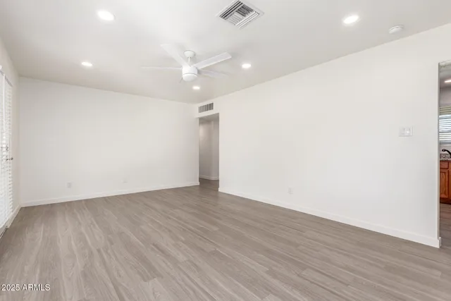 an empty room with wooden floor and ceiling fan