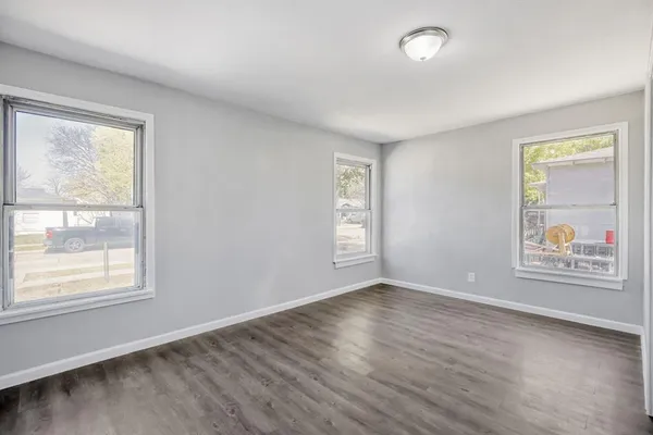 a view of an empty room with a window and wooden floor