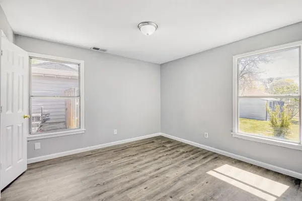 a view of empty room with window and wooden floor