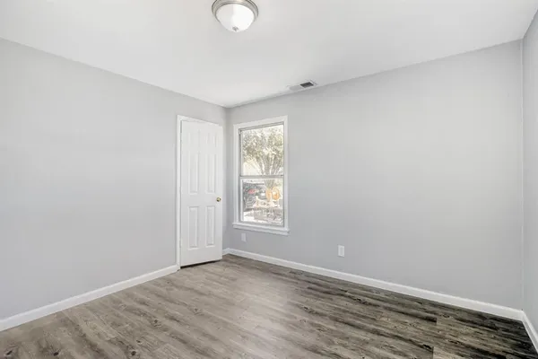 an empty room with wooden floor and window
