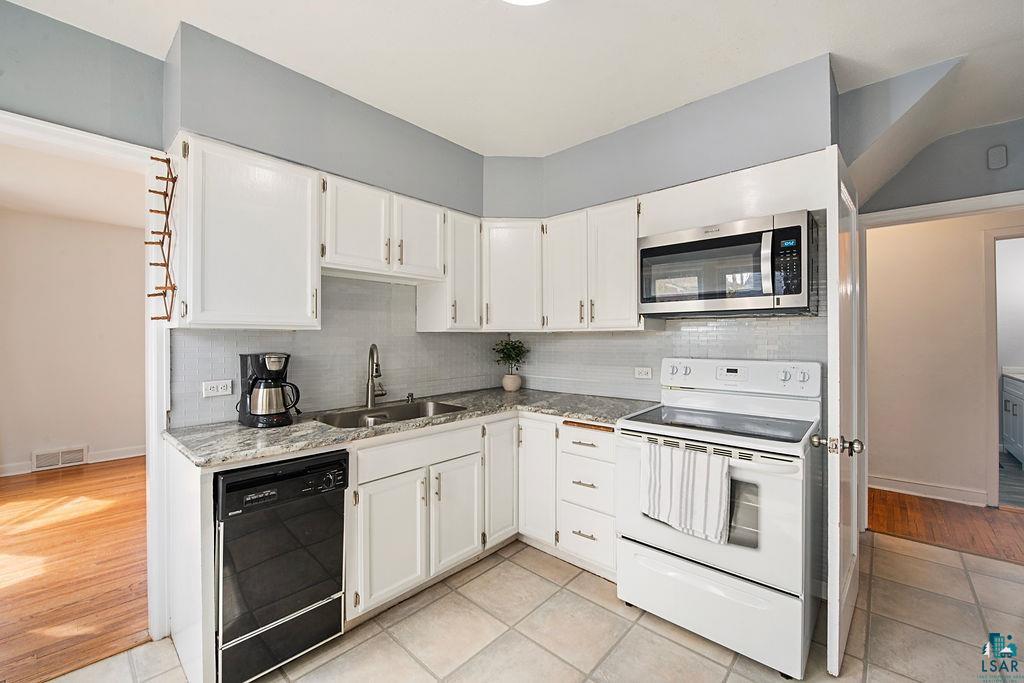 122 3rd Street Cloquet, MN 55720 - Photo 5 of 42 Kitchen featuring white cabinetry, light-toned countertops, a stainless steel over-the-range microwave, a white electric range, and a black dishwasher