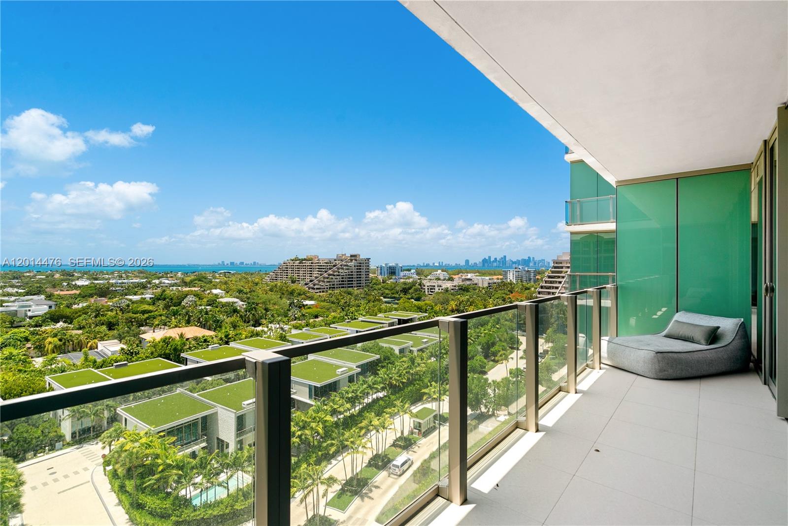 360 Ocean Drive, Unit 1106S Key Biscayne, FL 33149 - Photo 17 of 67 Private Balcony – The spacious balcony offers glass railings, a lounge area, and expansive views across lush greenery, surrounding residences, and the distant skyline. This outdoor setting extends the living space with an impressive open-air backdrop.