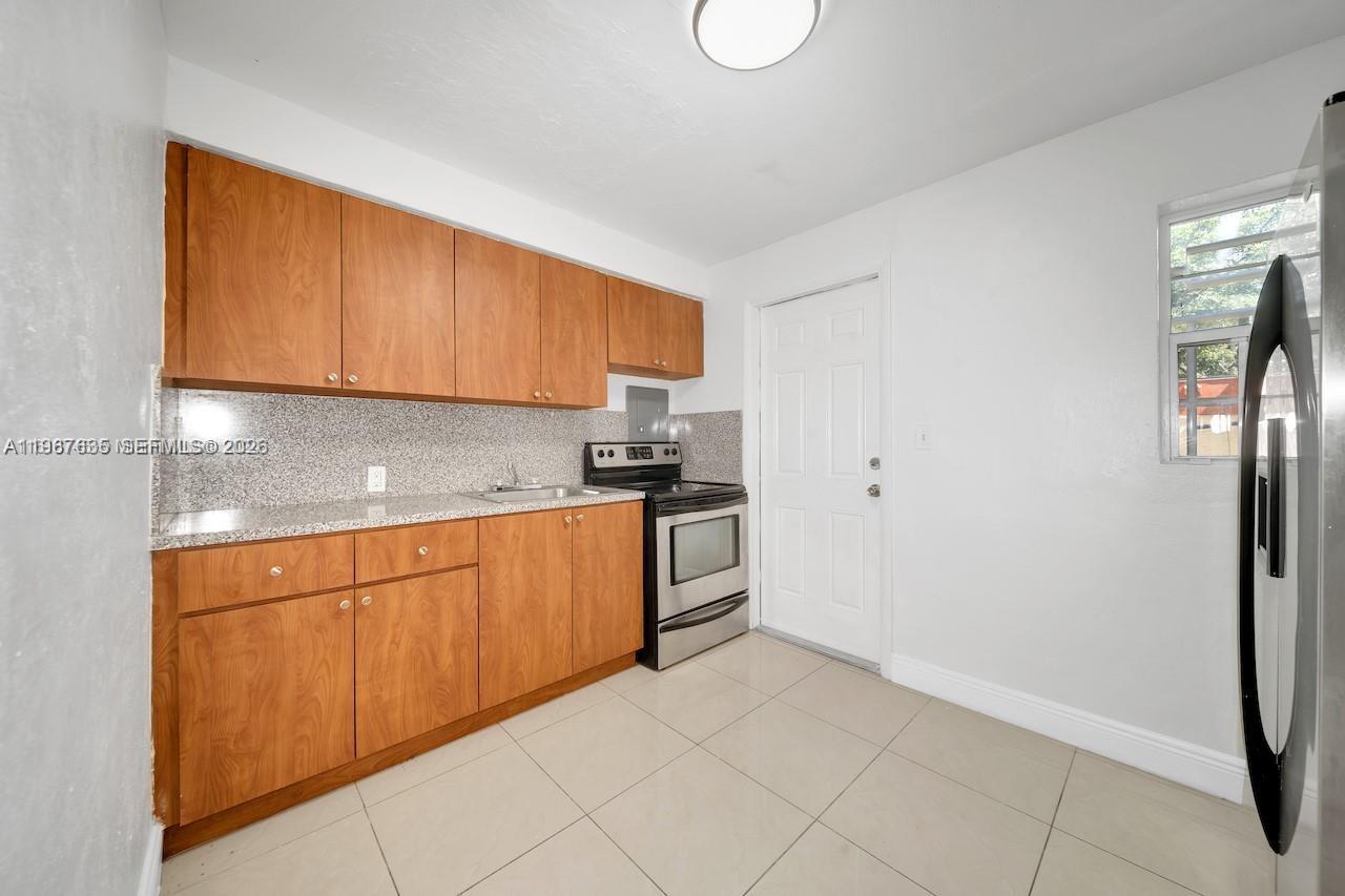 5545 Northwest 3rd Avenue, Unit W Miami, FL 33127 - Photo 2 of 8 a kitchen with granite countertop a refrigerator sink and cabinets