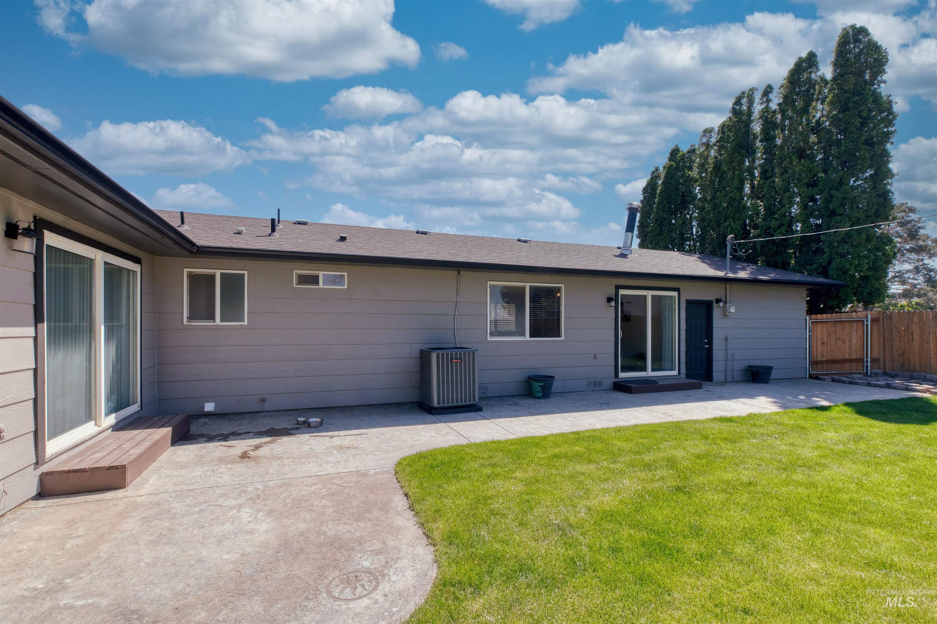 20803 Friends Road Greenleaf, ID 83626 - Photo 23 of 39 Expansive concrete patio with a manicured lawn, featuring a sliding glass door and an additional exterior door