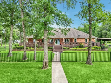 a front view of a house with a big yard and potted plants and large trees