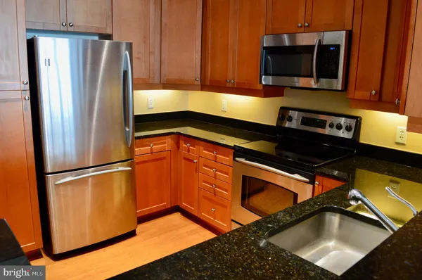 a kitchen with stainless steel appliances granite countertop a refrigerator a stove and a microwave