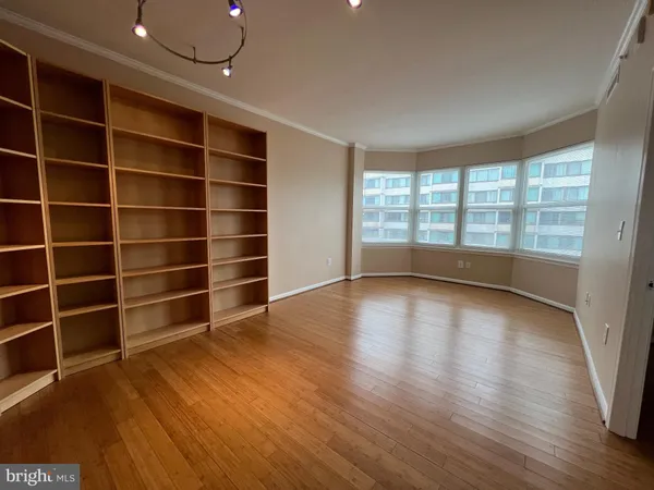 a view of an empty room with a window and wooden floor