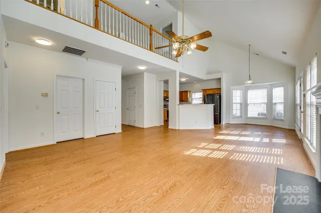 a view of an empty room with kitchen and a window