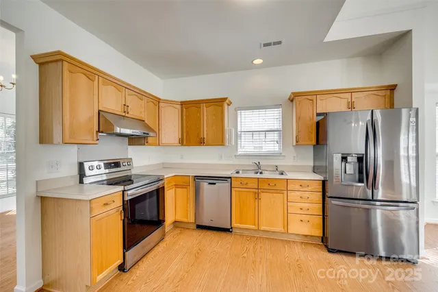 a kitchen with stainless steel appliances granite countertop a stove a sink dishwasher a refrigerator and a microwave oven with wooden floor