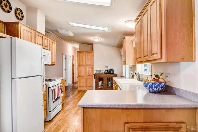 a kitchen with stainless steel appliances granite countertop a refrigerator a sink dishwasher a stove and a dining table with wooden floor