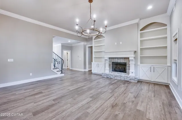 a view of an empty room with wooden floor fireplace and a window