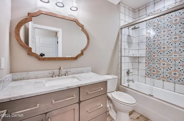 a bathroom with a granite countertop sink toilet and shower