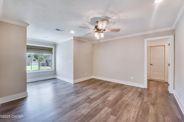 a view of an empty room with glass door and wooden floor