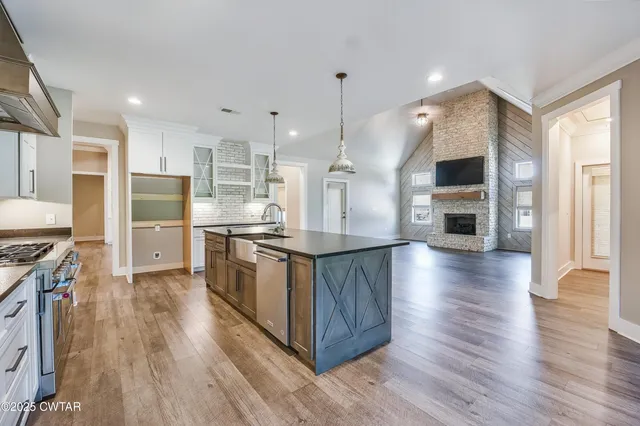 a large kitchen with stainless steel appliances granite countertop a large counter top and wooden floors