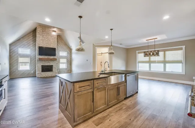 a large kitchen with stainless steel appliances granite countertop a stove and a wooden floors