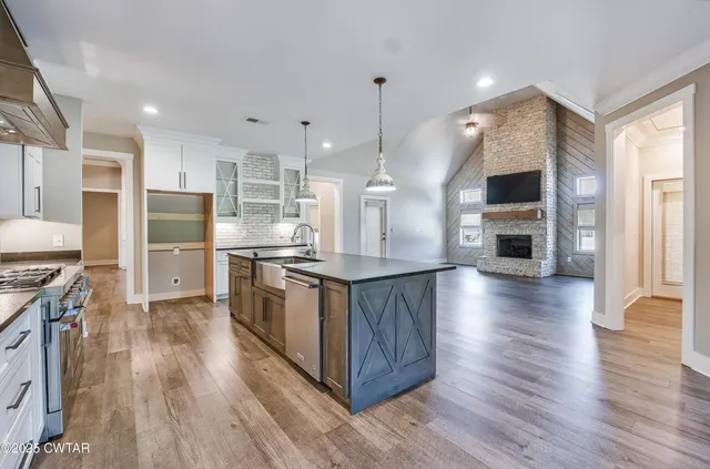 a large kitchen with stainless steel appliances granite countertop a large counter top and wooden floors