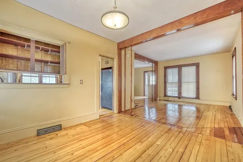 a view of empty room with wooden floor and fireplace