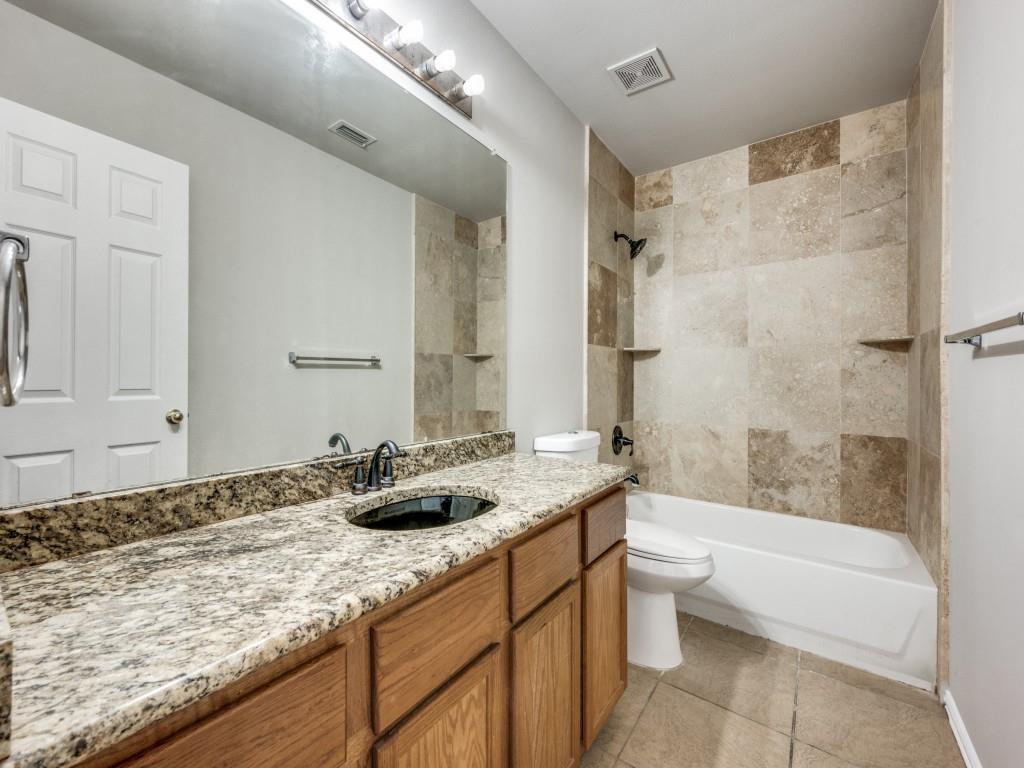 4445 Stones River Road Grand Prairie, TX 75052 - Photo 11 of 13 a bathroom with a granite countertop sink a toilet and bathtub