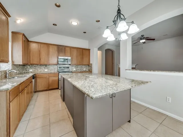 a kitchen with kitchen island granite countertop a sink a counter top space appliances and cabinets