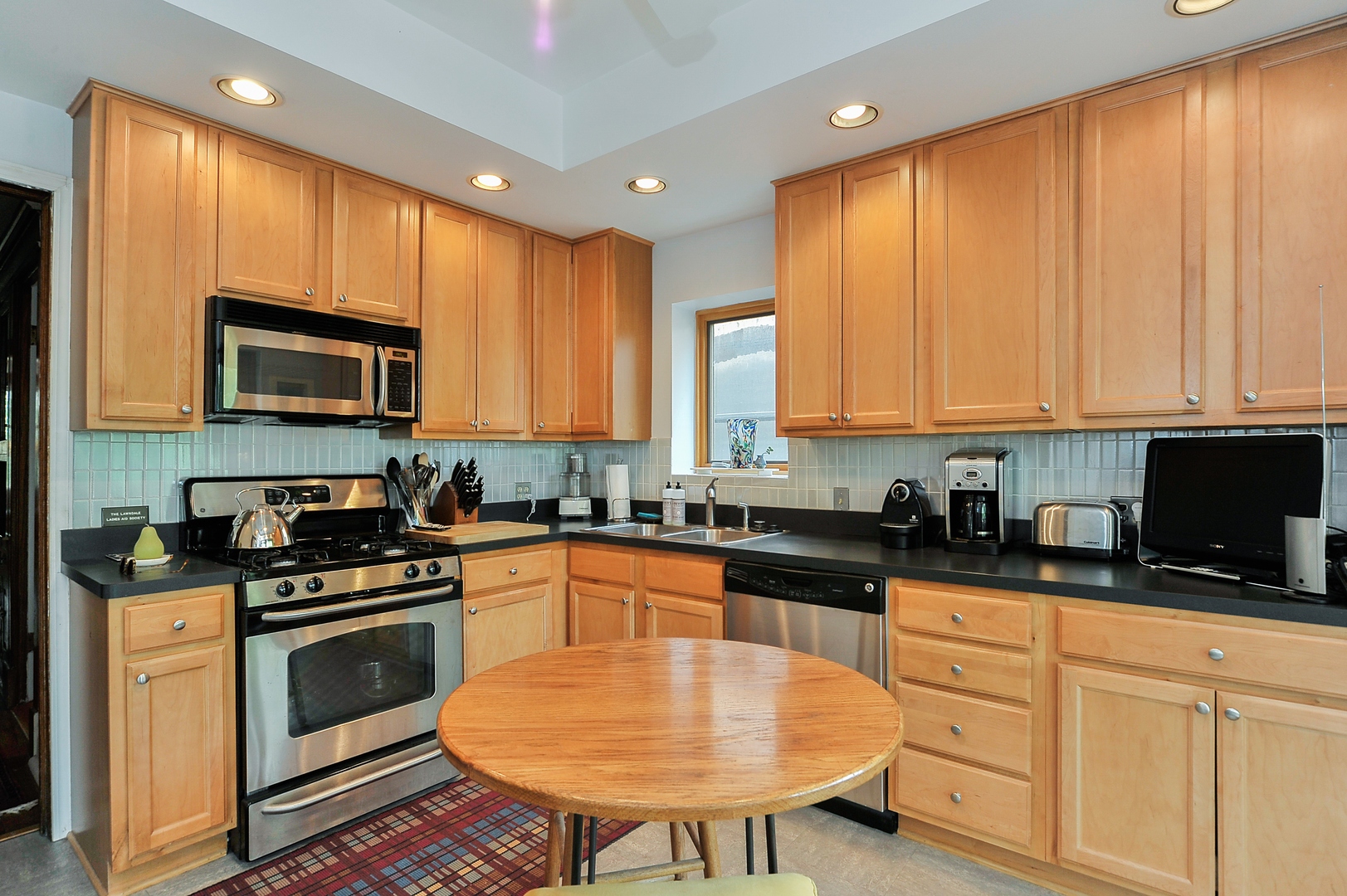 3729 North Wayne Avenue, Unit 2 Chicago, IL 60613 - Photo 6 of 17 a kitchen with stainless steel appliances granite countertop a stove a sink dishwasher and a microwave oven with wooden cabinets