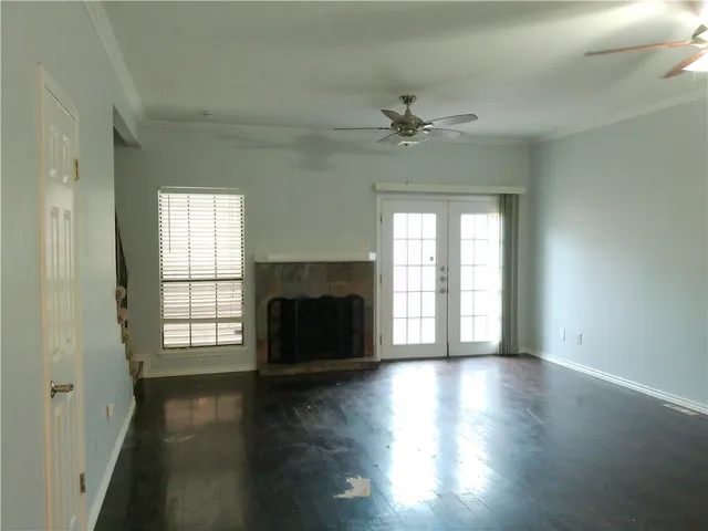 an empty room with wooden floor fireplace and windows