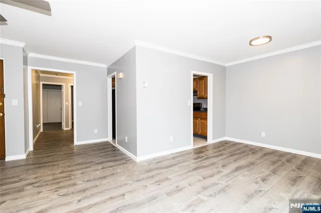 a view of an empty room with wooden floor and closet