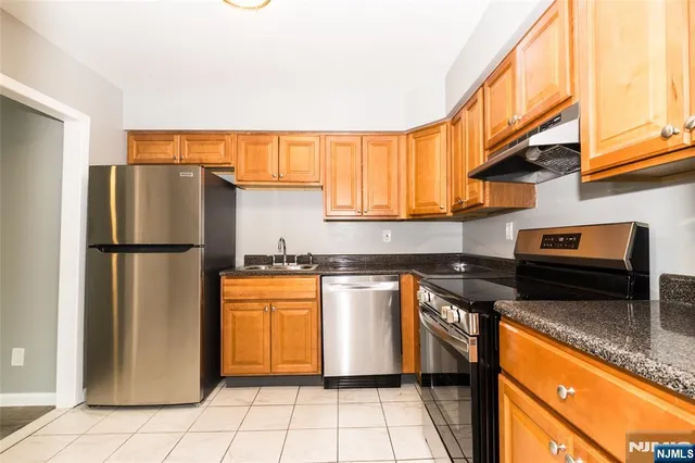 a kitchen with stainless steel appliances granite countertop a refrigerator a stove and a sink with cabinets